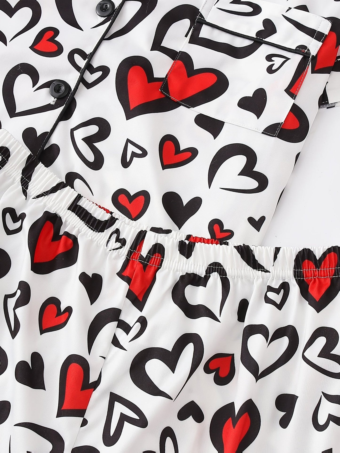White satin-look short-sleeve pajama set with red and black heart print, piped trim, chest pocket and elastic waist shorts in 95% Polyester 5% Elastane — silky stretch travel-ready loungewear