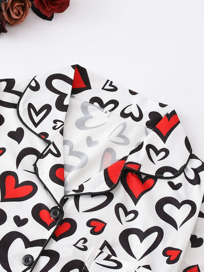 White satin-look short-sleeve pajama set with red and black heart print, piped trim, chest pocket and elastic waist shorts in 95% Polyester 5% Elastane — silky stretch travel-ready loungewear