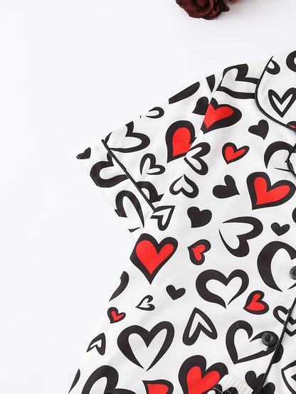 White satin-look short-sleeve pajama set with red and black heart print, piped trim, chest pocket and elastic waist shorts in 95% Polyester 5% Elastane — silky stretch travel-ready loungewear