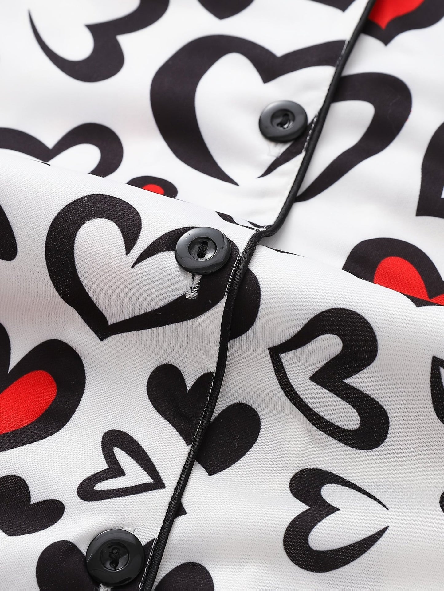 White satin-look short-sleeve pajama set with red and black heart print, piped trim, chest pocket and elastic waist shorts in 95% Polyester 5% Elastane — silky stretch travel-ready loungewear