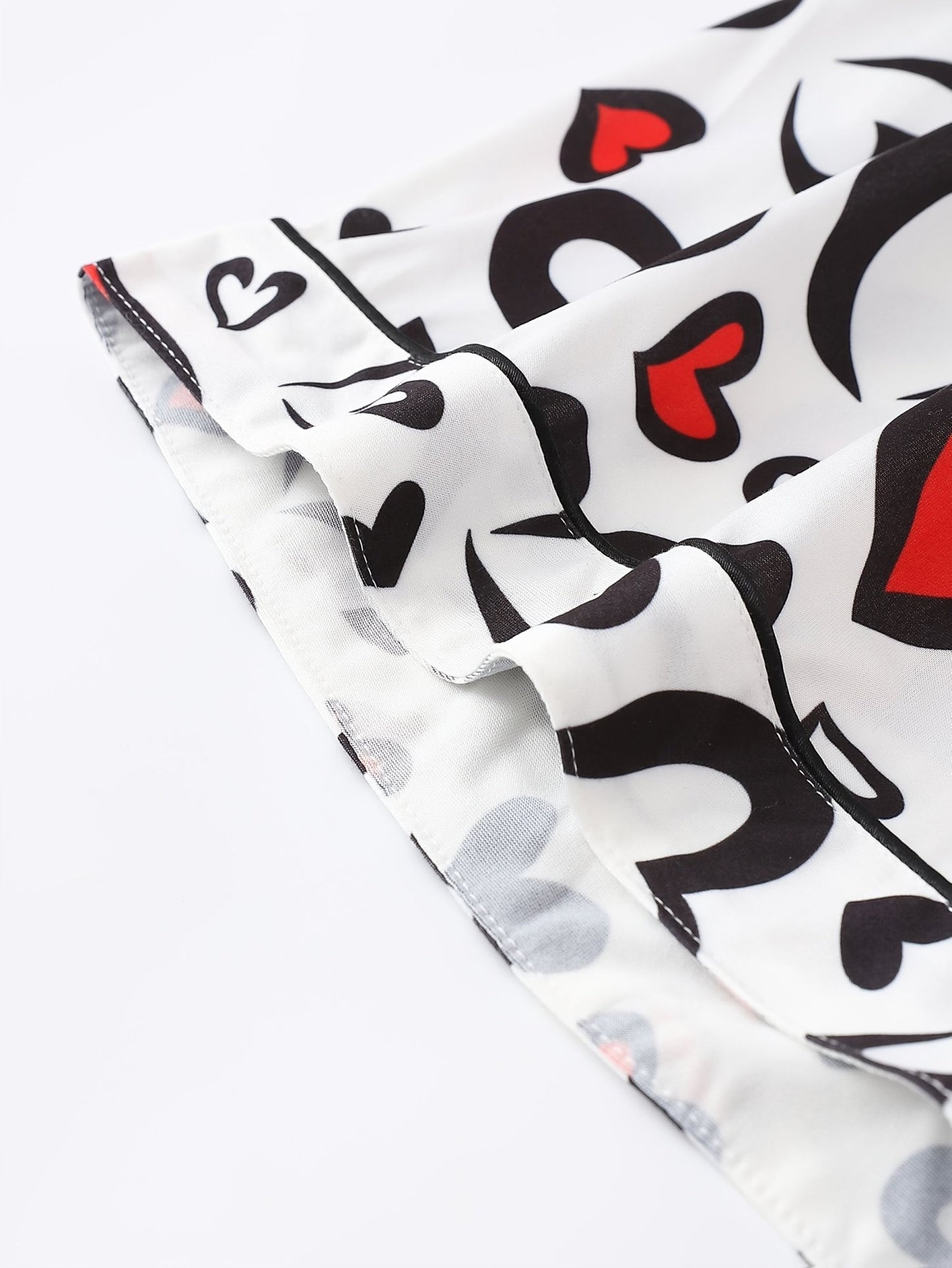 White satin-look short-sleeve pajama set with red and black heart print, piped trim, chest pocket and elastic waist shorts in 95% Polyester 5% Elastane — silky stretch travel-ready loungewear