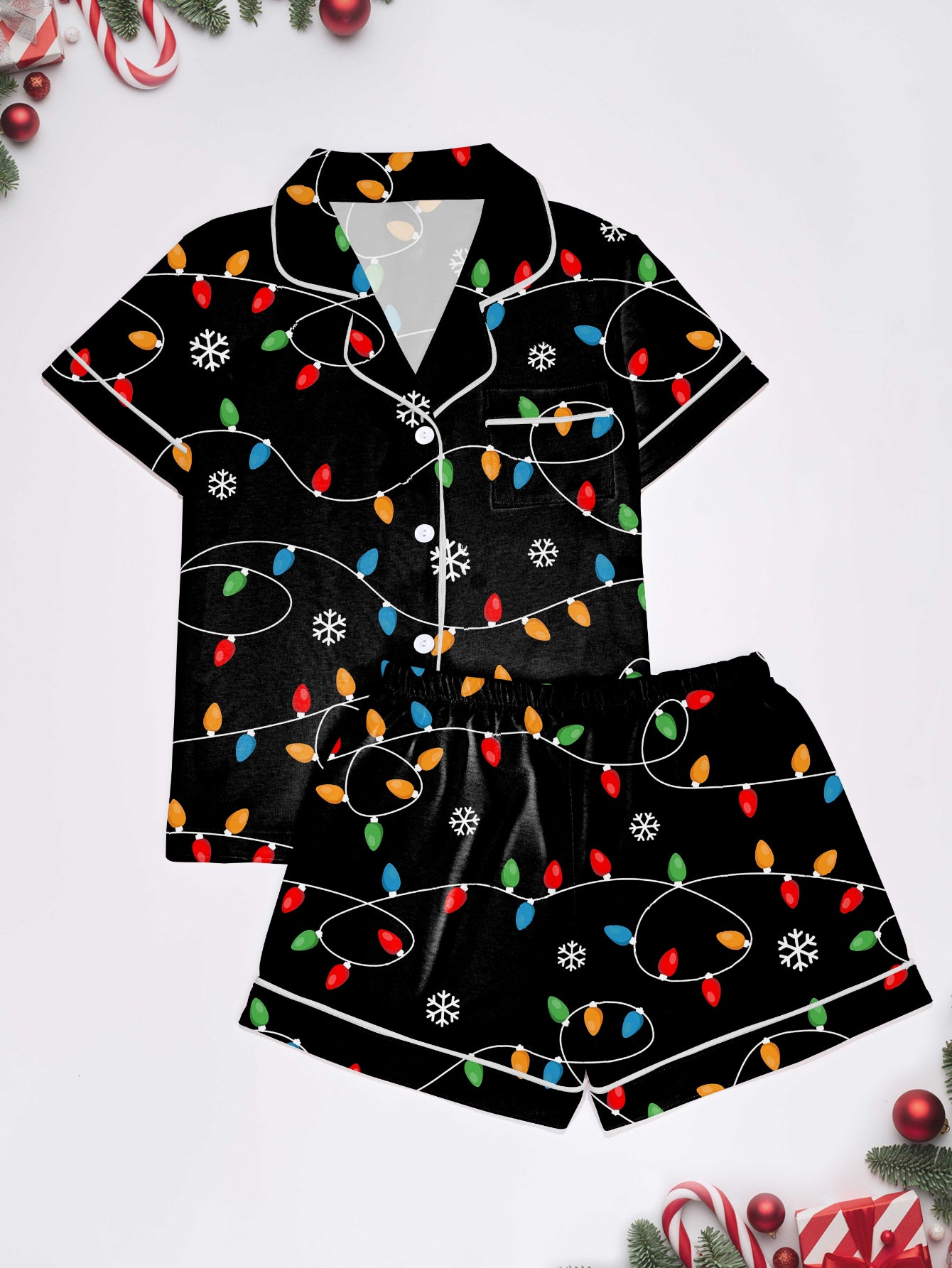 Black short-sleeve women’s pajama set with multicolor string-light and snowflake print — button-up top and elastic waist shorts with contrast piping
