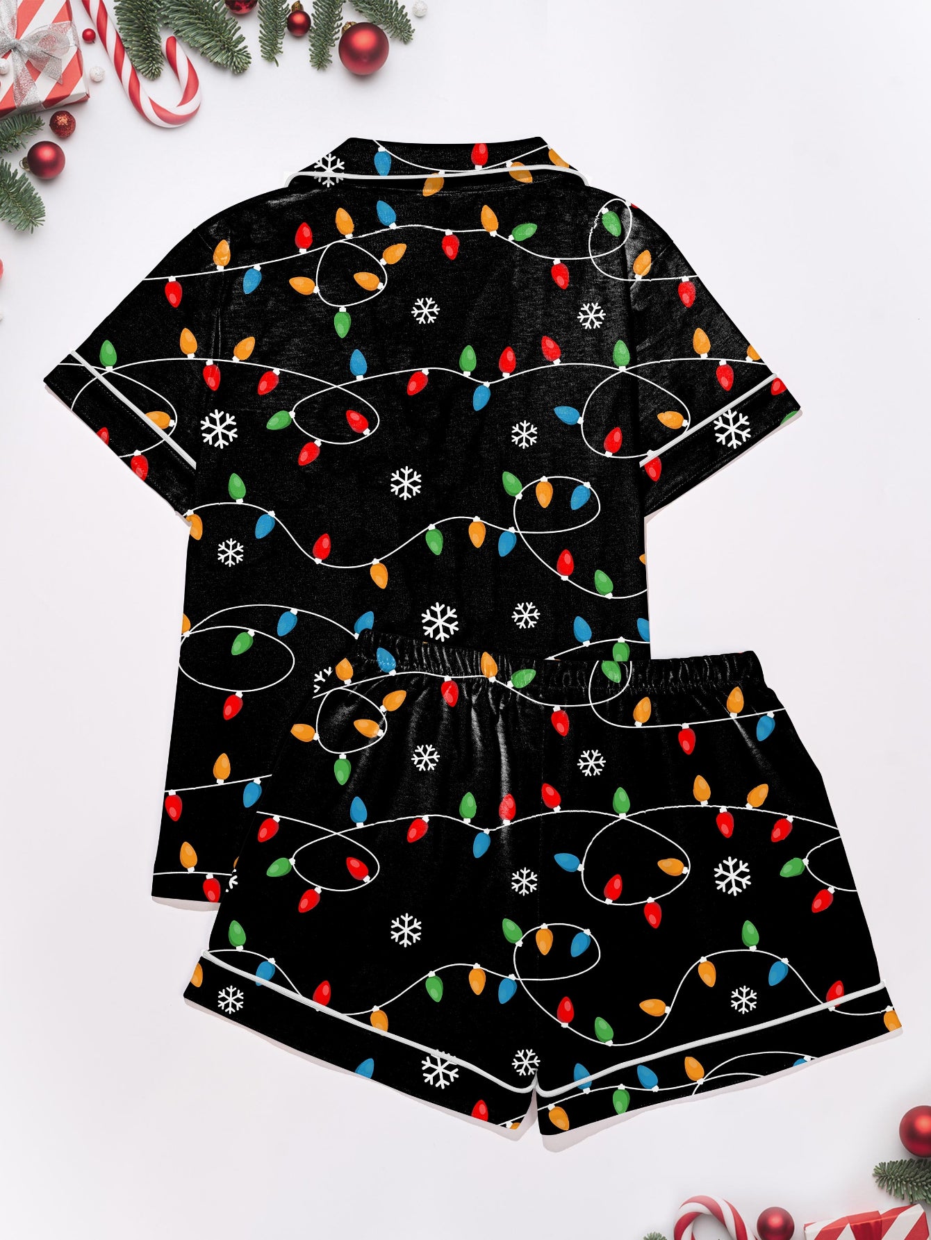 Black short-sleeve women’s pajama set with multicolor string-light and snowflake print — button-up top and elastic waist shorts with contrast piping