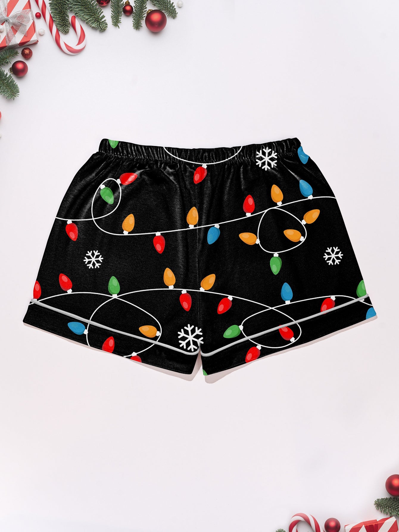 Black short-sleeve women’s pajama set with multicolor string-light and snowflake print — button-up top and elastic waist shorts with contrast piping