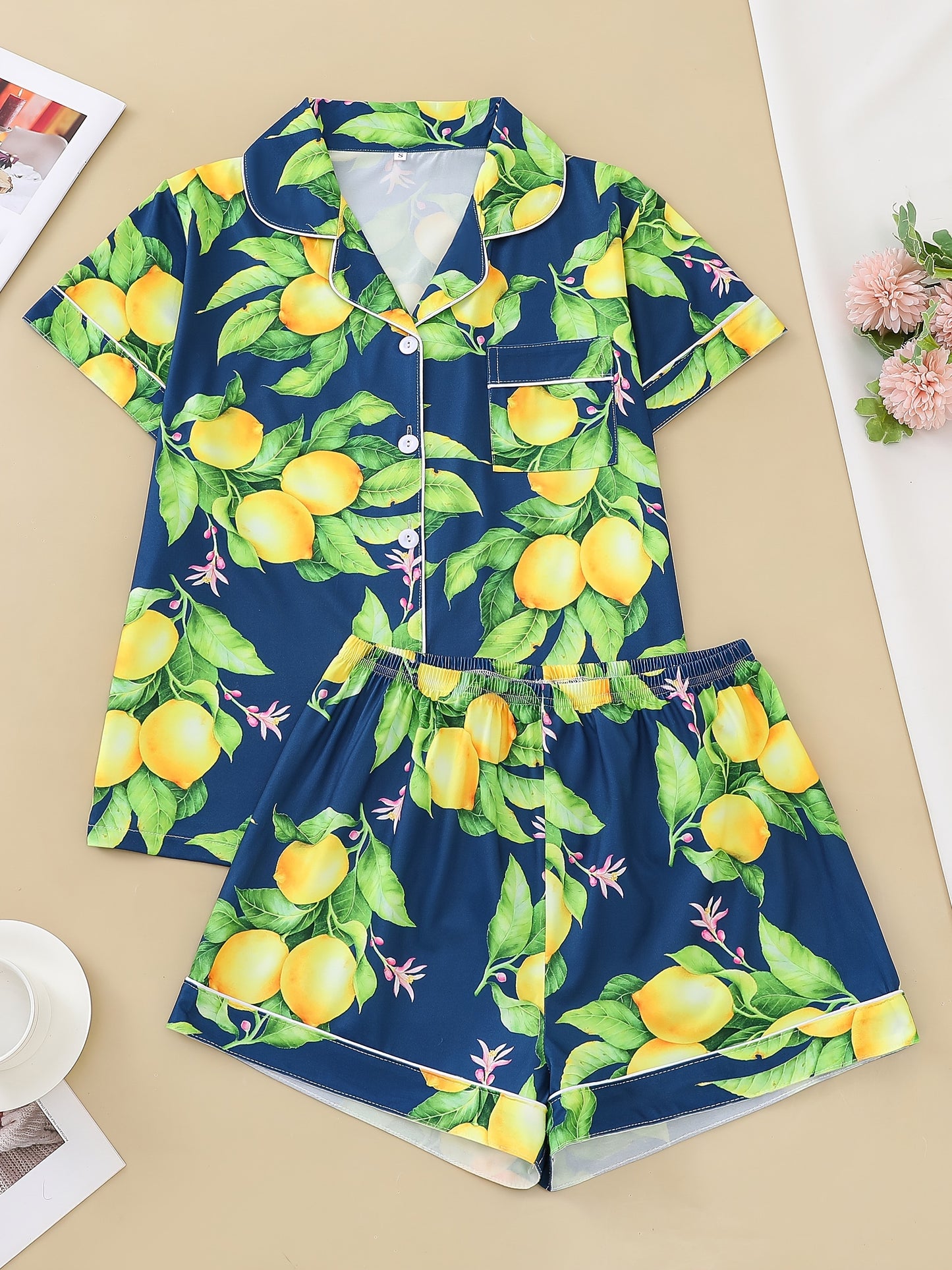 Navy satin-look pajama set with yellow lemon and green leaf print — short-sleeve button-up top with chest pocket and elastic waist shorts, 95% Polyester/5% Elastane