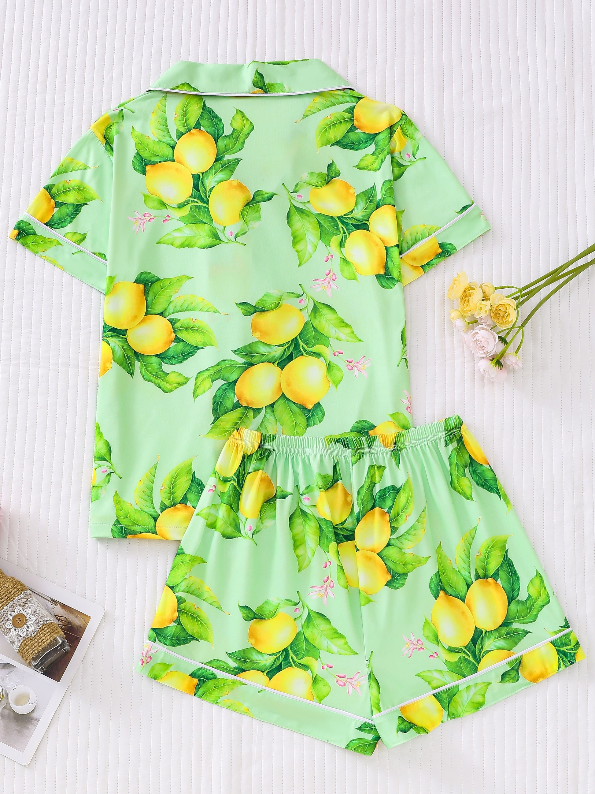Navy satin-look pajama set with yellow lemon and green leaf print — short-sleeve button-up top with chest pocket and elastic waist shorts, 95% Polyester/5% Elastane