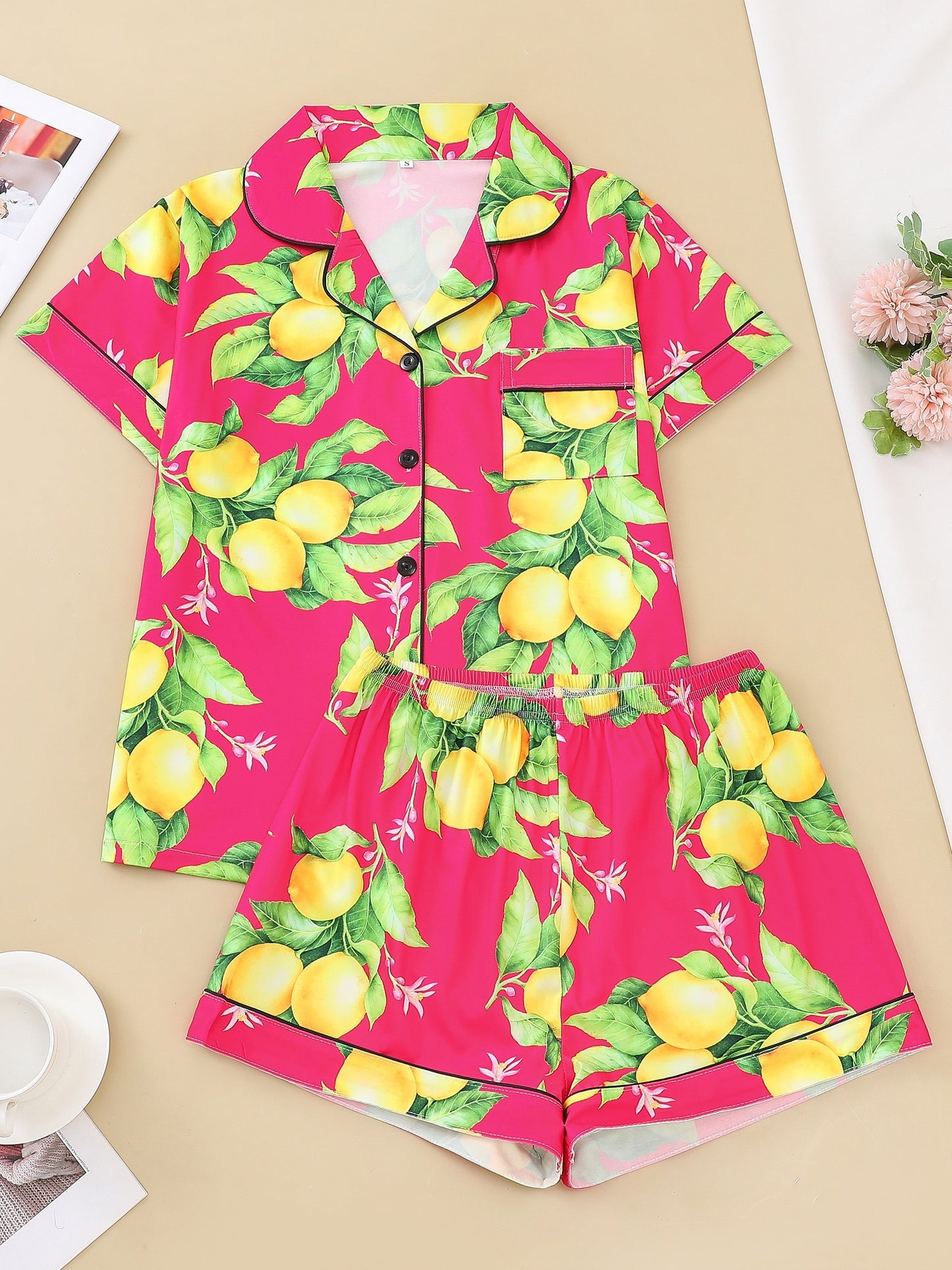 Navy satin-look pajama set with yellow lemon and green leaf print — short-sleeve button-up top with chest pocket and elastic waist shorts, 95% Polyester/5% Elastane