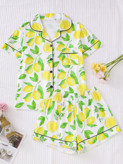 White satin-look pajama set with bright yellow lemon and green leaf print — short-sleeve button-up top with chest pocket and elastic waist shorts, 95% Polyester/5% Elastane