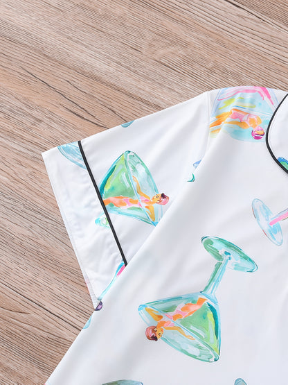 White satin-look pajama set with watercolor martini glass print, short-sleeve button top with piped pocket and elastic waist shorts — 95% Polyester/5% Elastane, silky and breathable