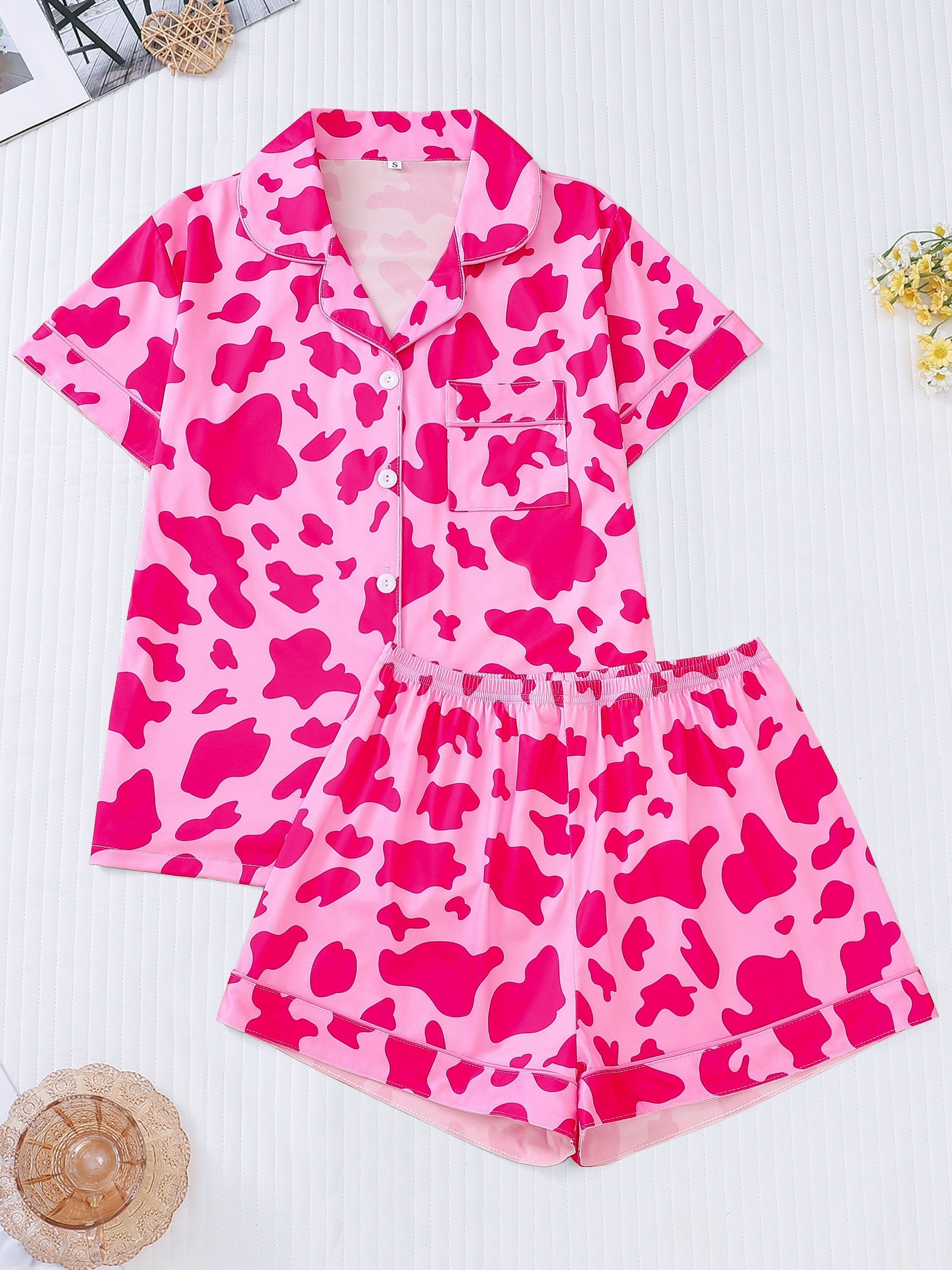 White silk‑touch modal short‑sleeve pajama top and elastic waist shorts with black cow‑spot print and aqua piping