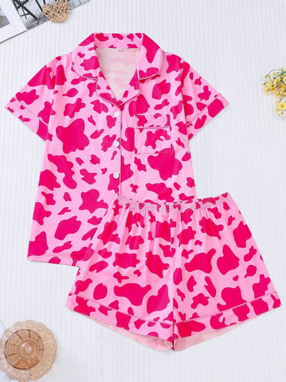 White silk‑touch modal short‑sleeve pajama top and elastic waist shorts with black cow‑spot print and aqua piping