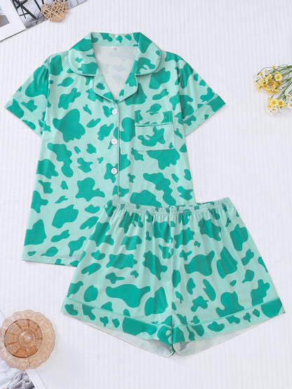 White silk‑touch modal short‑sleeve pajama top and elastic waist shorts with black cow‑spot print and aqua piping