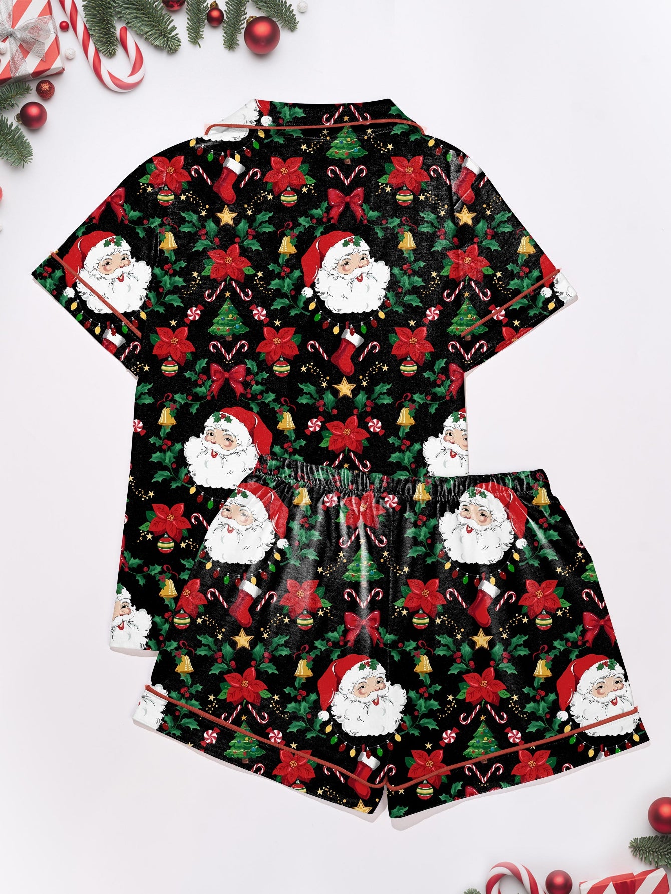 Woman wearing black short-sleeve pajama set with Santa, poinsettia and candy cane print — button-up top and elastic waist shorts with red piping