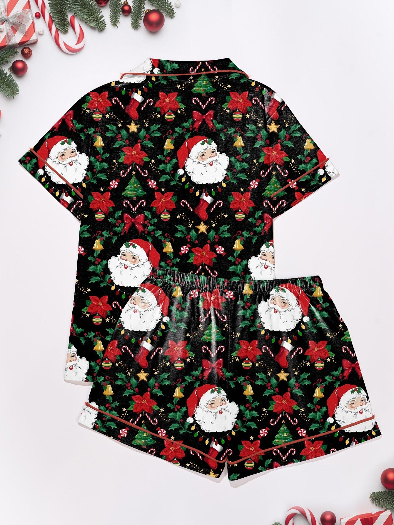 Woman wearing black short-sleeve pajama set with Santa, poinsettia and candy cane print — button-up top and elastic waist shorts with red piping