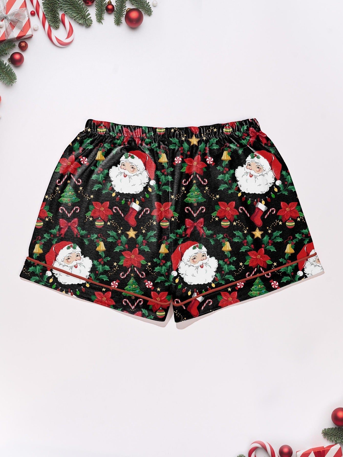 Woman wearing black short-sleeve pajama set with Santa, poinsettia and candy cane print — button-up top and elastic waist shorts with red piping
