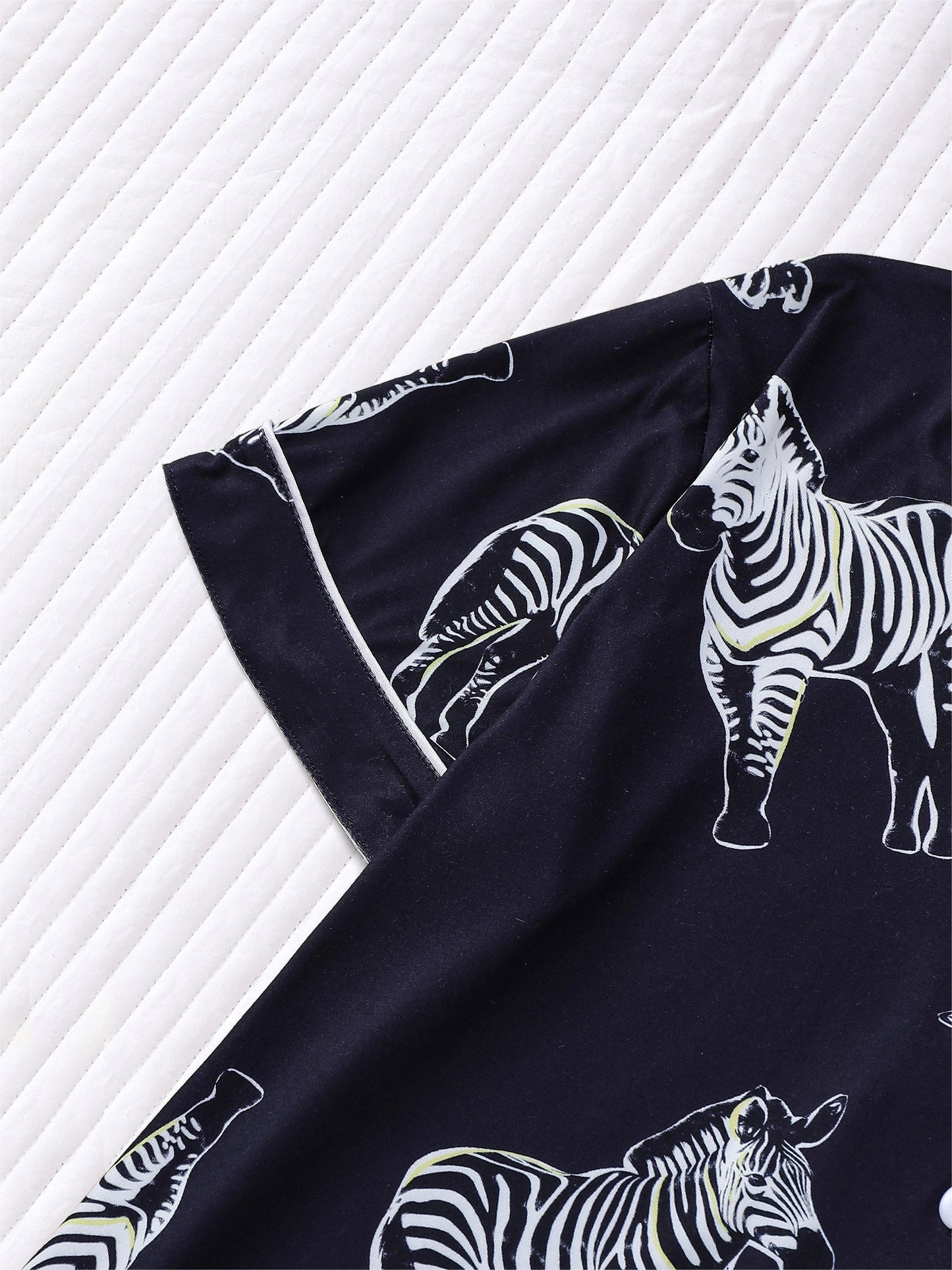 Navy satin-look short pajama set with black-and-white zebra print — short-sleeve button-up top and elastic waist shorts, 95% Polyester/5% Elastane, lightweight and silky