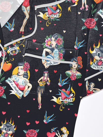 Black silk‑touch modal pajama set with colorful tattoo‑flash print — short‑sleeve button top and elastic waist shorts with white piping