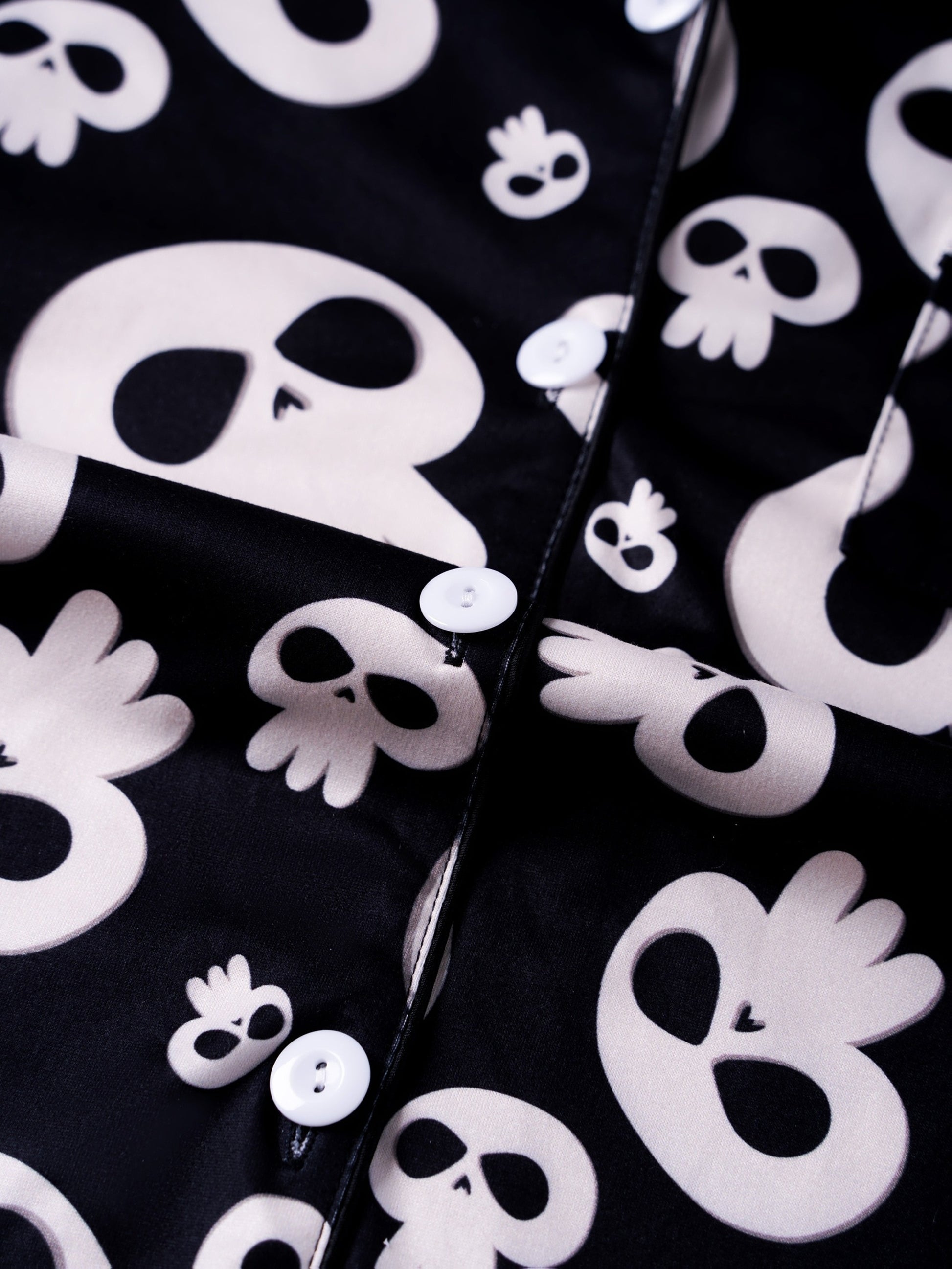 Black modal pajama set with cream skull motifs — short‑sleeve button top and elastic waist shorts with piping