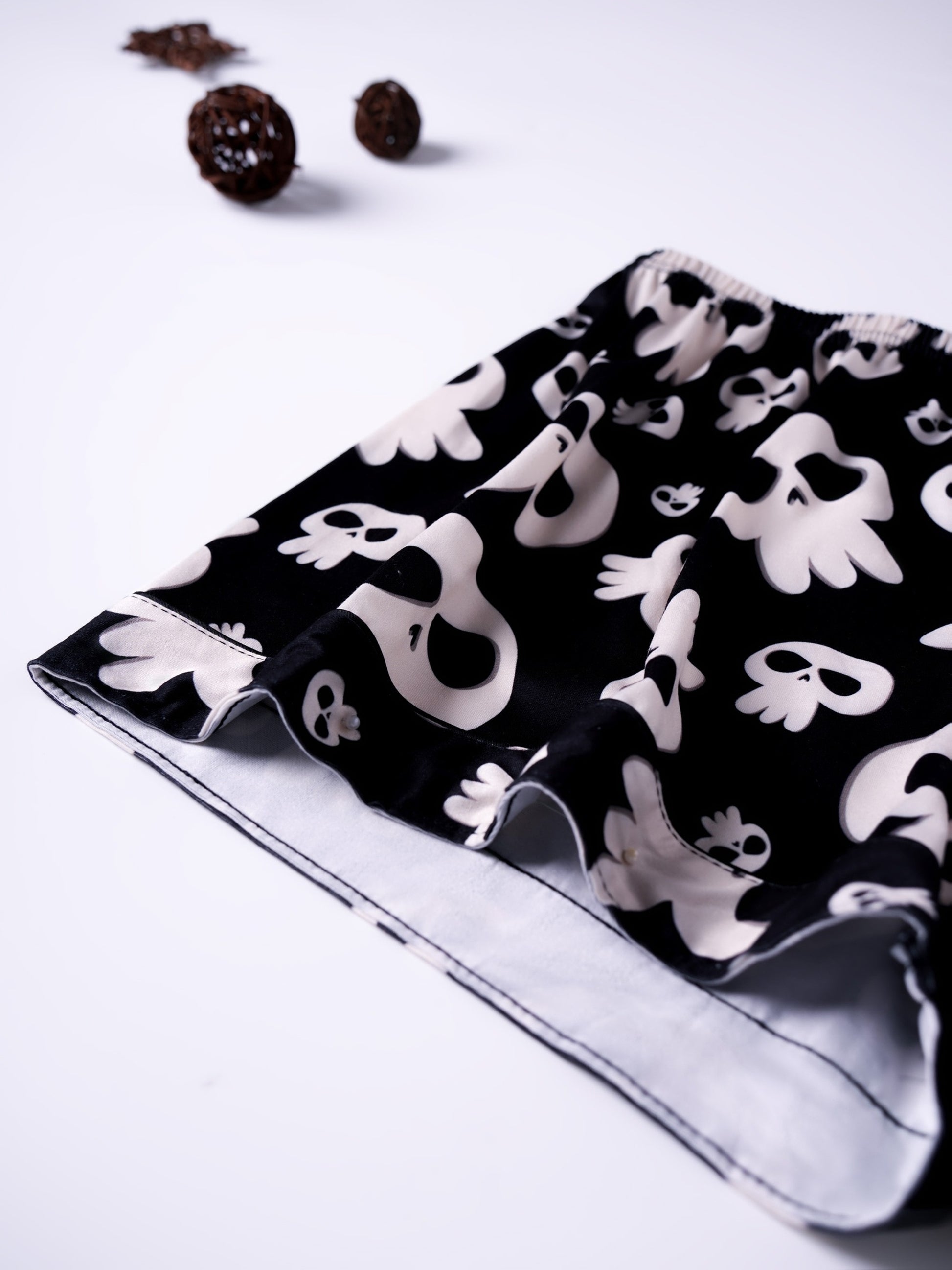 Black modal pajama set with cream skull motifs — short‑sleeve button top and elastic waist shorts with piping