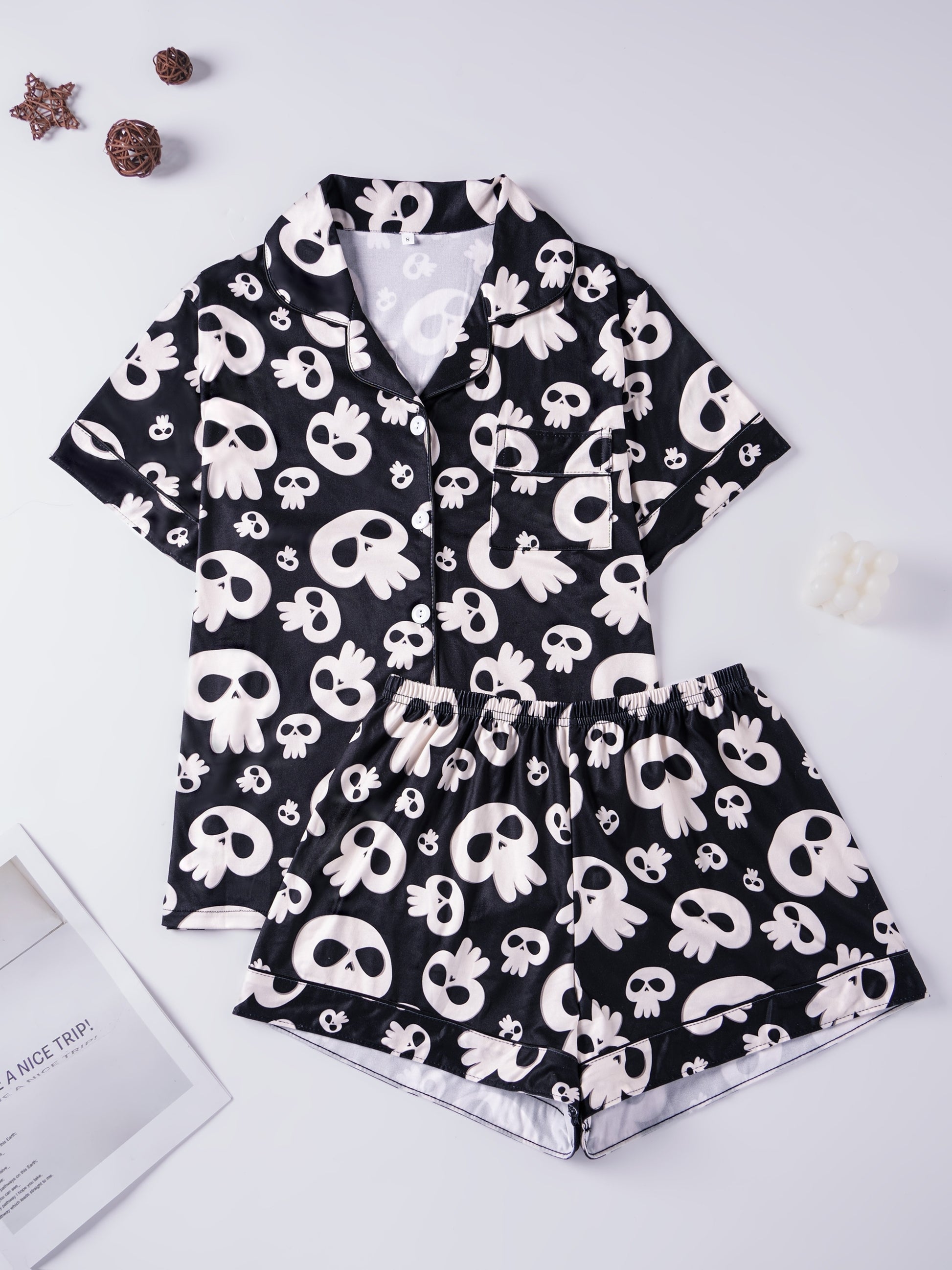 Black modal pajama set with cream skull motifs — short‑sleeve button top and elastic waist shorts with piping