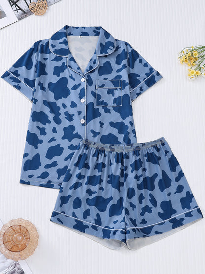 White silk‑touch modal short‑sleeve pajama top and elastic waist shorts with black cow‑spot print and aqua piping