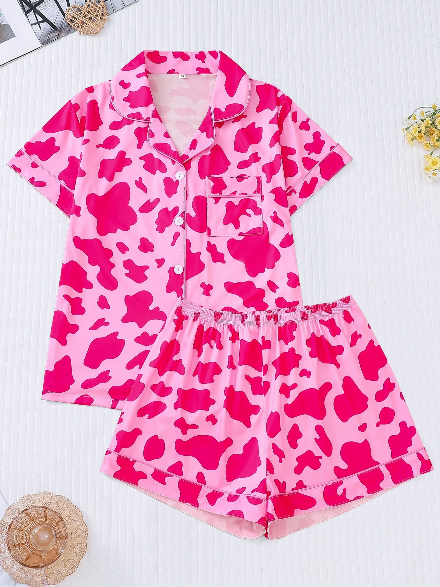 White silk‑touch modal short‑sleeve pajama top and elastic waist shorts with black cow‑spot print and aqua piping