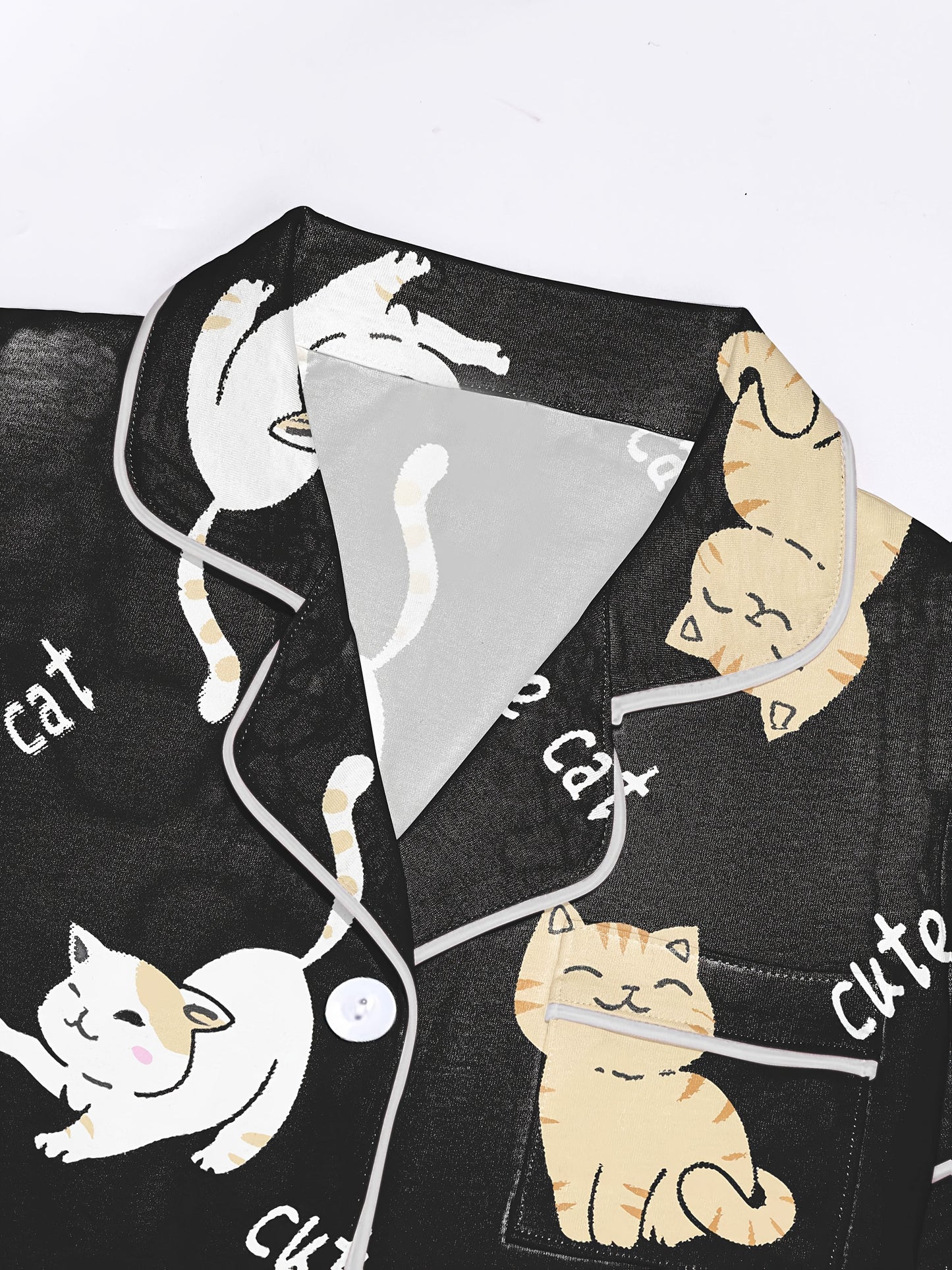 Black modal short‑sleeve pajama set with cream and tan cat print — button top with notch collar and elastic waist shorts with gray piping