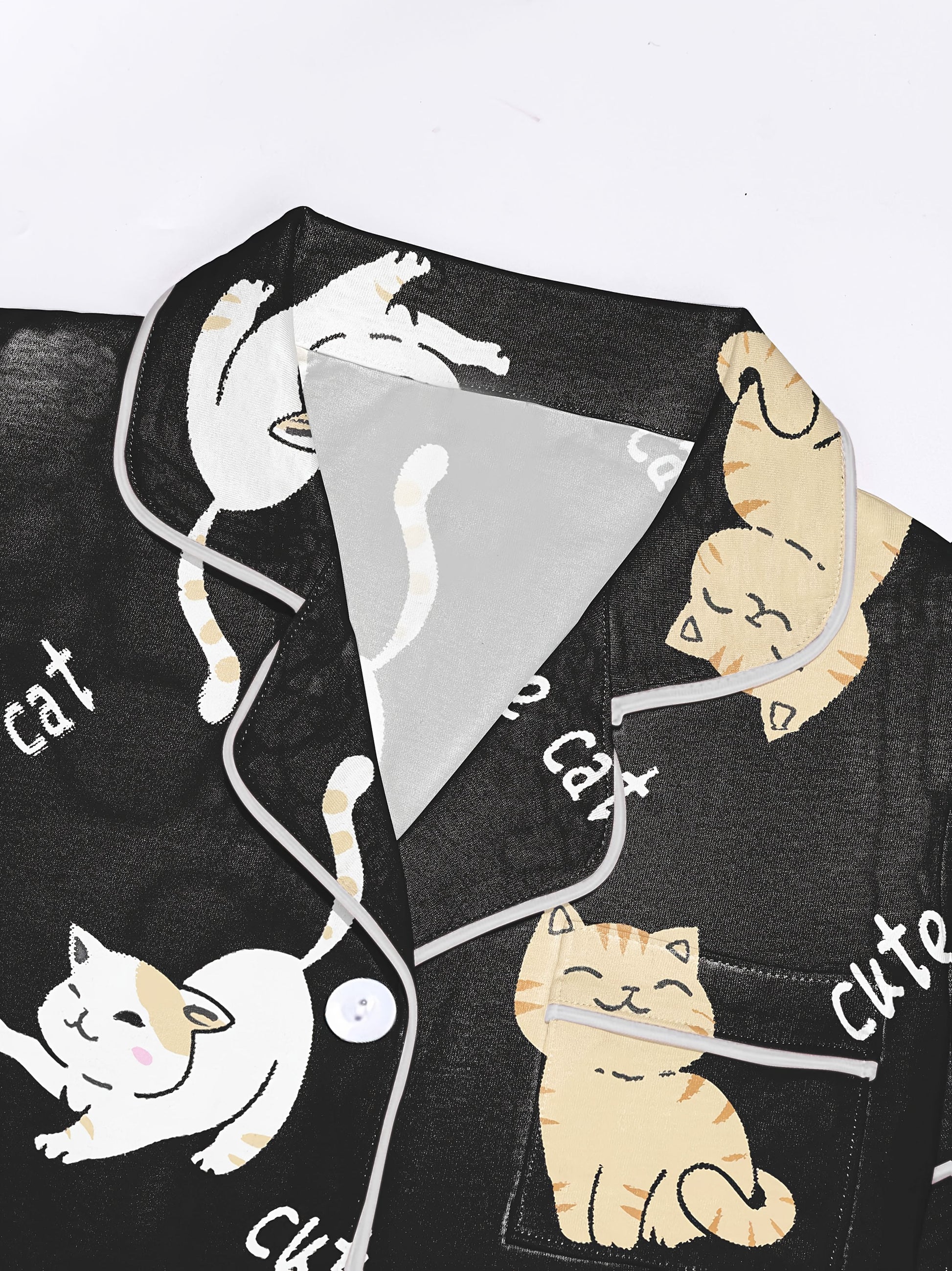 Black modal short‑sleeve pajama set with cream and tan cat print — button top with notch collar and elastic waist shorts with gray piping