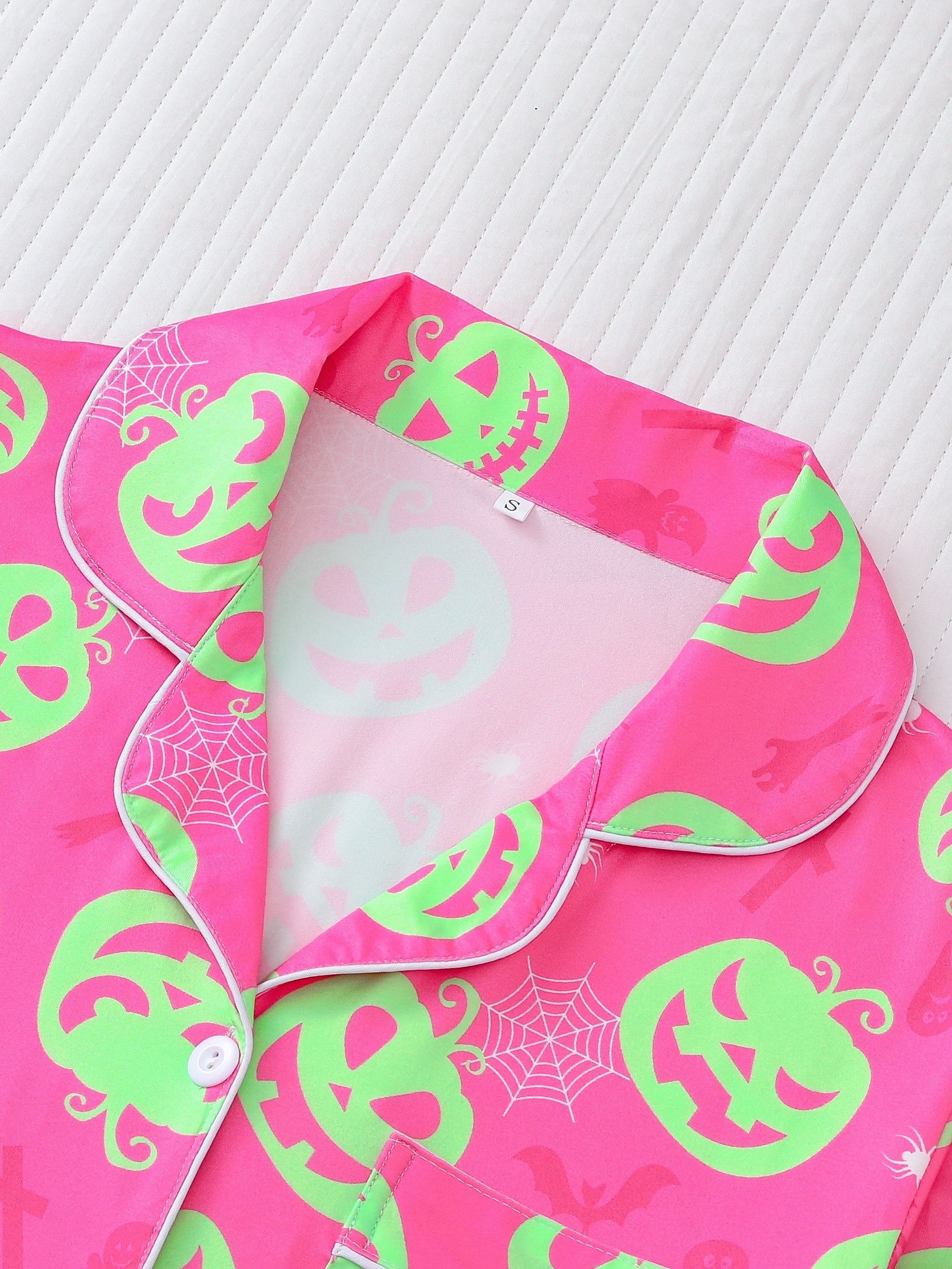 Hot-pink satin-look short pajama set with neon lime pumpkin jack-o’-lanterns and spiderweb print — short-sleeve relaxed top and elastic waist shorts, 95% Polyester/5% Elastane, lightweight and breathable