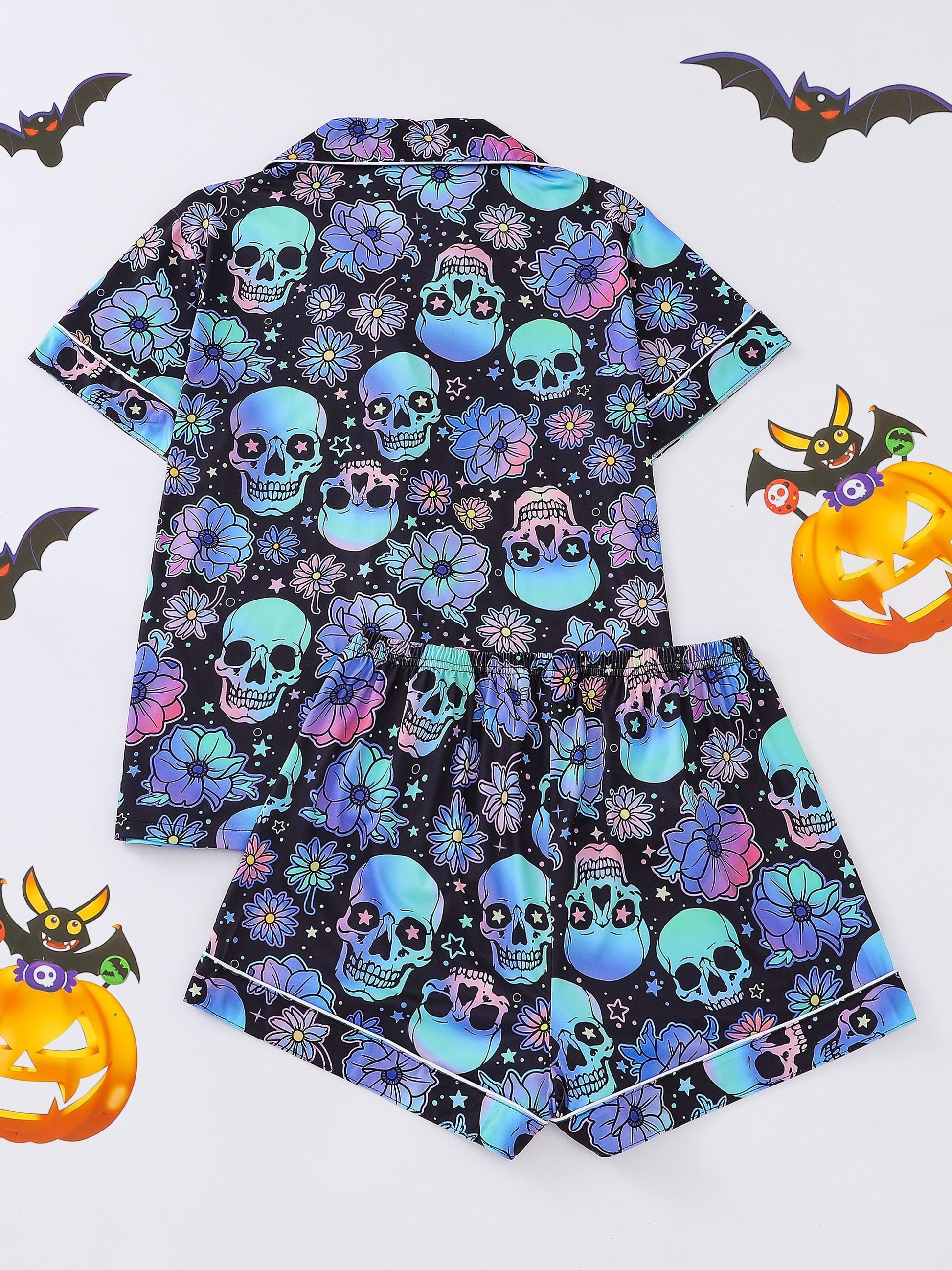 Black satin-look pajama set with neon blue and violet skull and floral print — short-sleeve button-up top with chest pocket and elastic waist shorts, 95% Polyester/5% Elastane