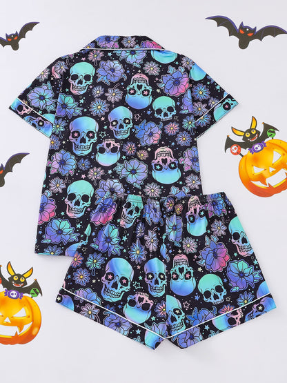 Black satin-look pajama set with neon blue and violet skull and floral print — short-sleeve button-up top with chest pocket and elastic waist shorts, 95% Polyester/5% Elastane