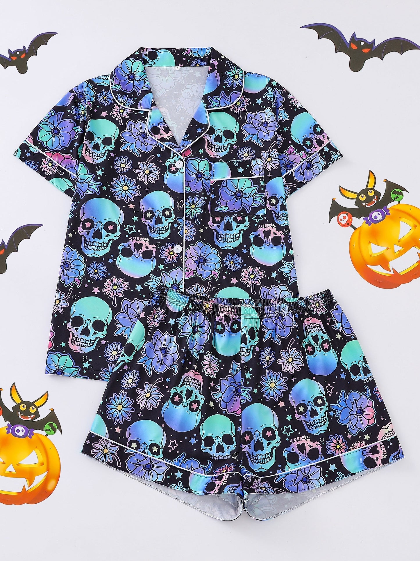 Black satin-look pajama set with neon blue and violet skull and floral print — short-sleeve button-up top with chest pocket and elastic waist shorts, 95% Polyester/5% Elastane