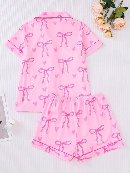Pink satin-look short sleeve pajama set with bow print and hearts, piped trim, chest pocket and elastic waist shorts in 95% Polyester 5% Elastane — silky stretch loungewear
