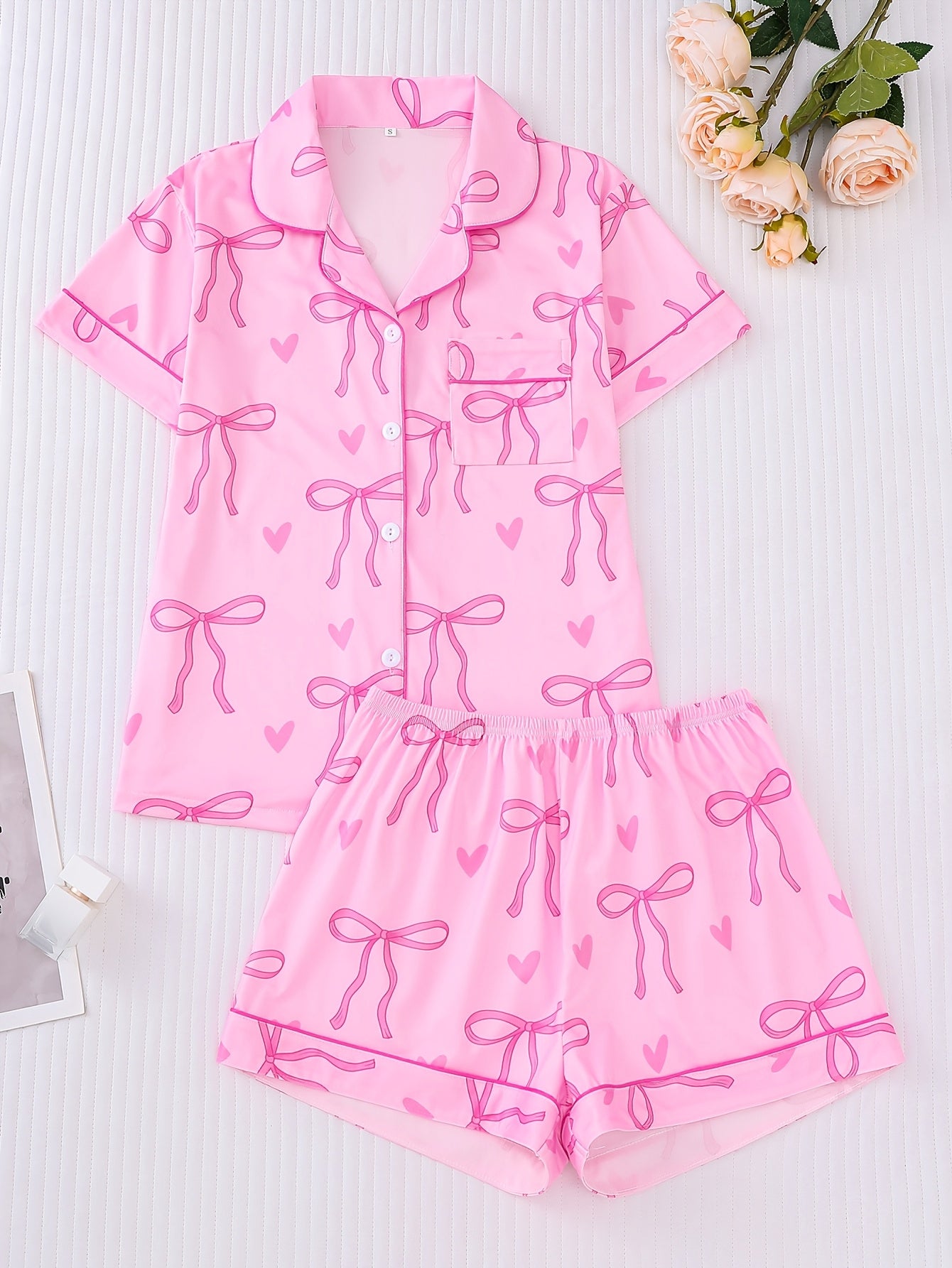 Pink satin-look short sleeve pajama set with bow print and hearts, piped trim, chest pocket and elastic waist shorts in 95% Polyester 5% Elastane — silky stretch loungewear