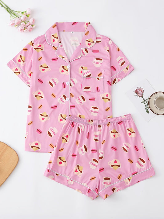 Pink satin-look short-sleeve pajama set with coffee cup and macaron print, piped trim, chest pocket and elastic waist shorts in 95% Polyester 5% Elastane — silky stretch travel-ready loungewear