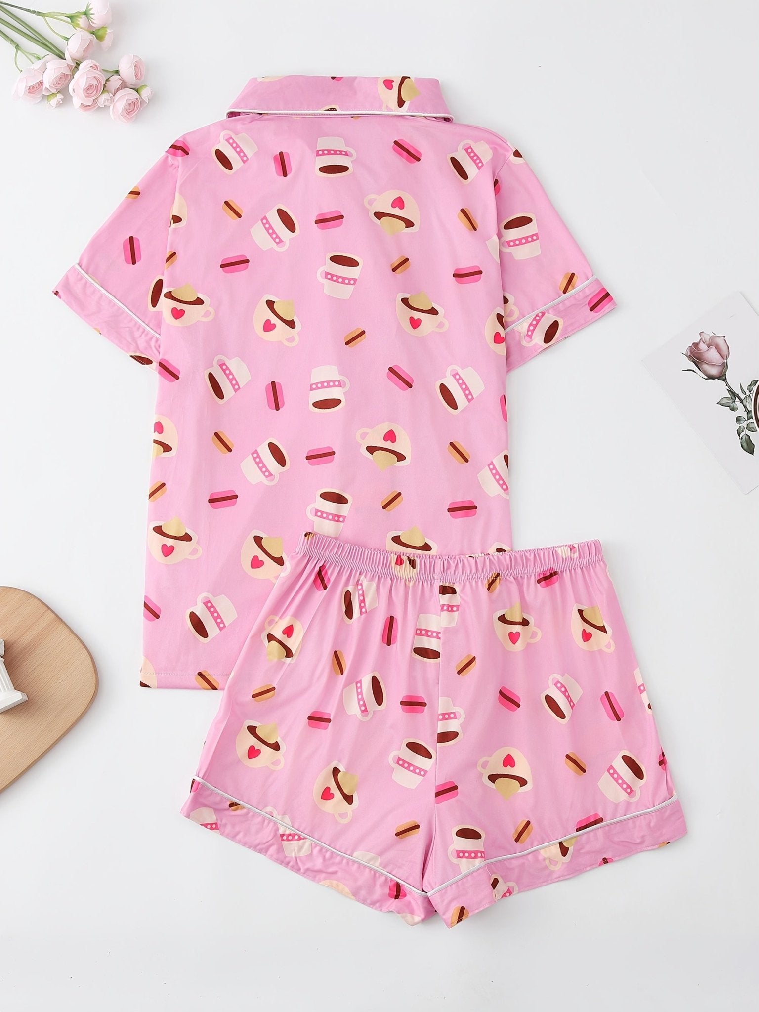 Pink satin-look short-sleeve pajama set with coffee cup and macaron print, piped trim, chest pocket and elastic waist shorts in 95% Polyester 5% Elastane — silky stretch travel-ready loungewear