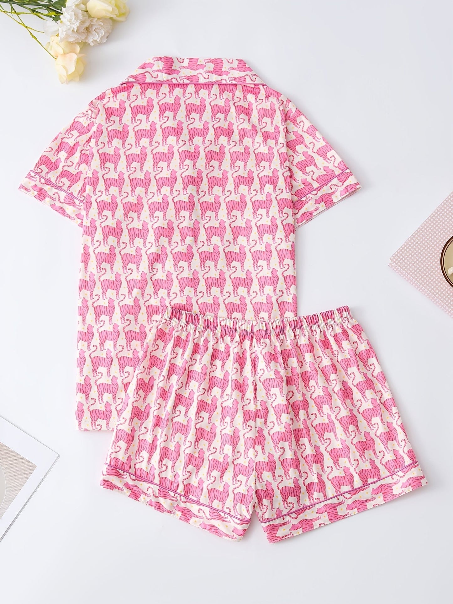 Pink satin-look short-sleeve pajama set with repeating zebra print, piped trim and elastic waist shorts in 95% Polyester 5% Elastane — silky stretch travel-ready loungewear