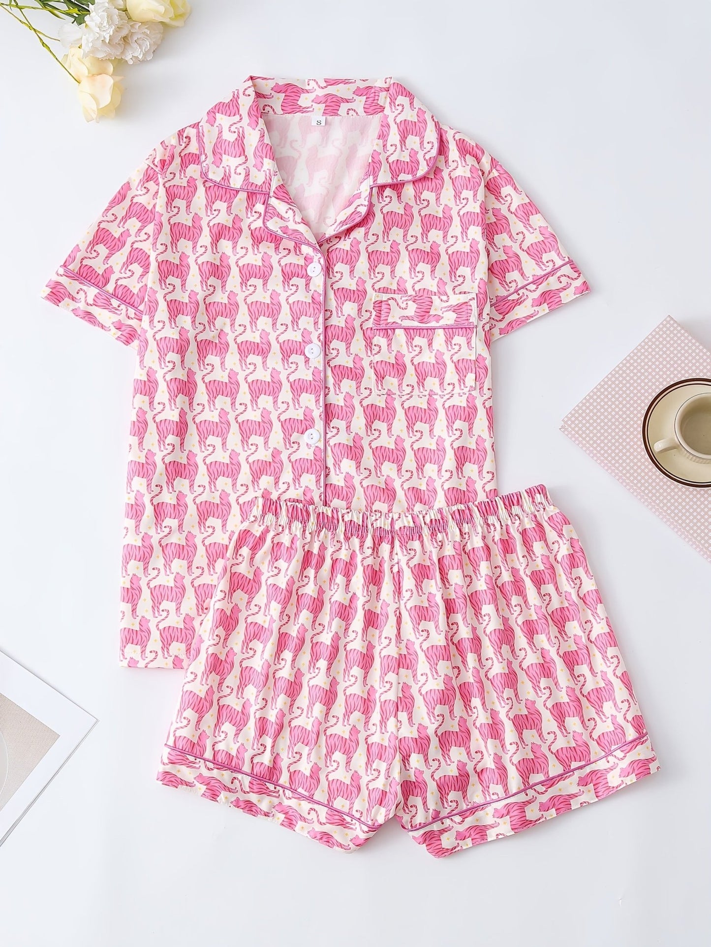 Pink satin-look short-sleeve pajama set with repeating zebra print, piped trim and elastic waist shorts in 95% Polyester 5% Elastane — silky stretch travel-ready loungewear