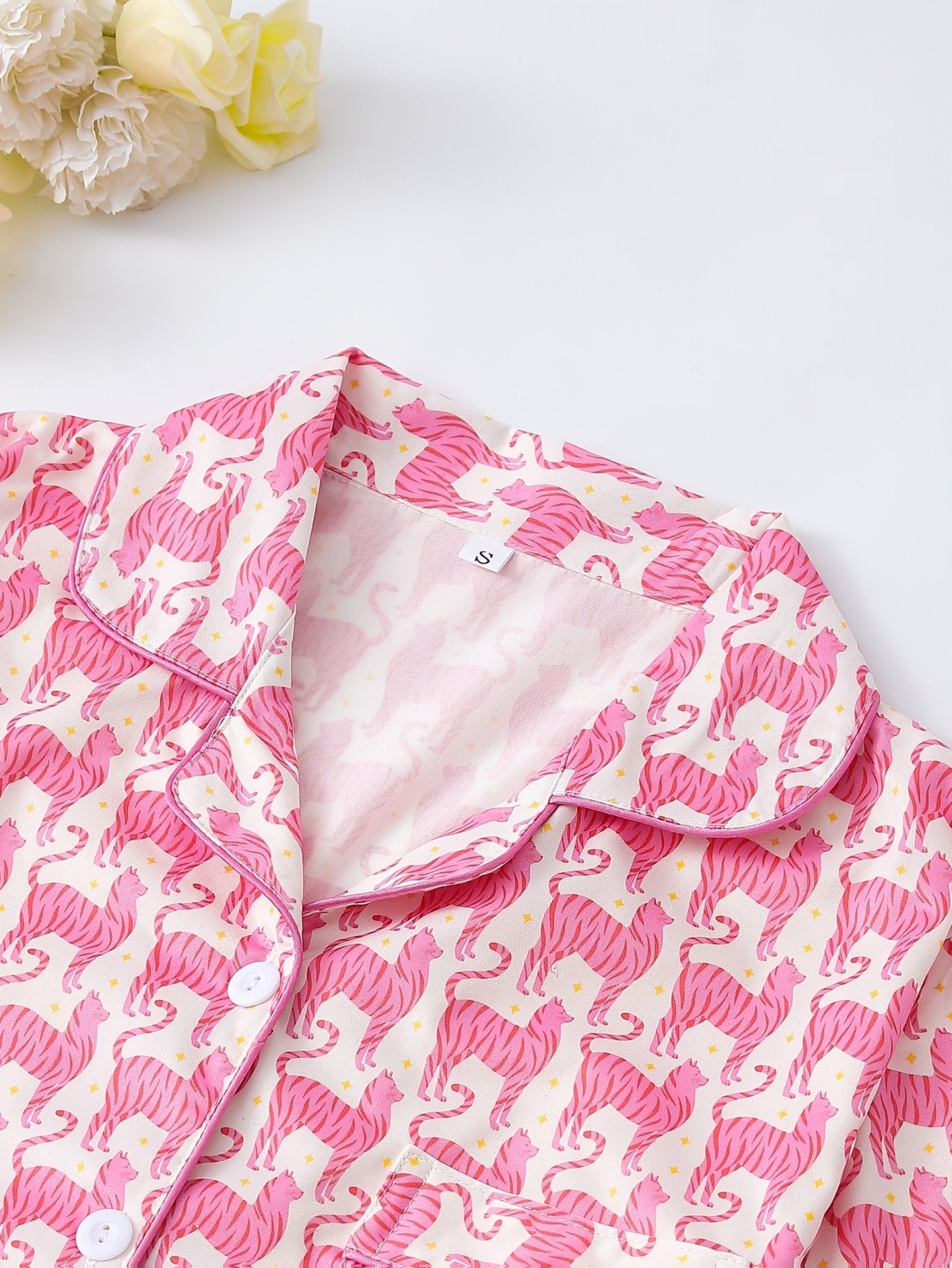 Pink satin-look short-sleeve pajama set with repeating zebra print, piped trim and elastic waist shorts in 95% Polyester 5% Elastane — silky stretch travel-ready loungewear