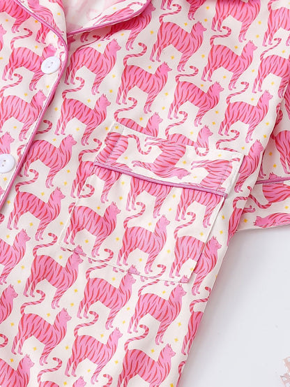 Pink satin-look short-sleeve pajama set with repeating zebra print, piped trim and elastic waist shorts in 95% Polyester 5% Elastane — silky stretch travel-ready loungewear