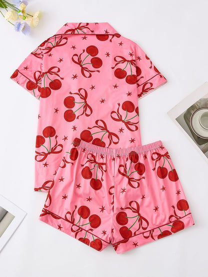 Pink satin-look short-sleeve pajama set with red cherry and bow print, piped trim, chest pocket and elastic waist shorts in 95% Polyester 5% Elastane