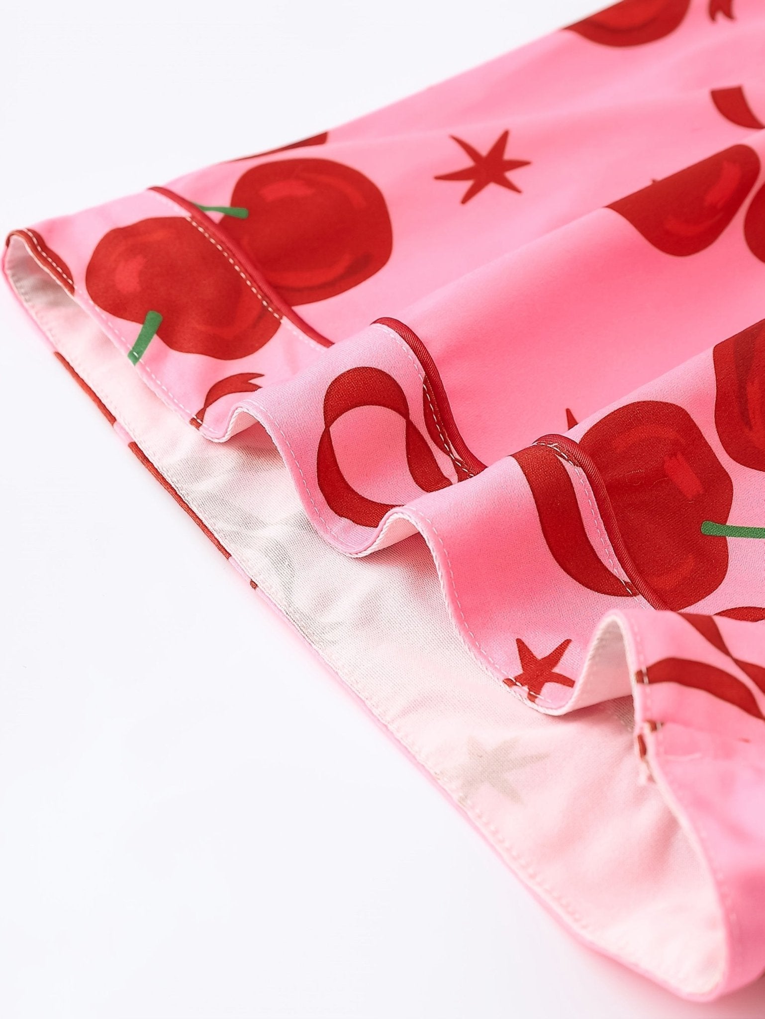 Pink satin-look short-sleeve pajama set with red cherry and bow print, piped trim, chest pocket and elastic waist shorts in 95% Polyester 5% Elastane