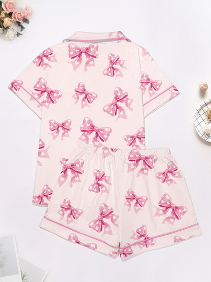 Pastel pink short-sleeve pajama set with heart-dotted bow print — button-up top and elastic waist shorts with pink piping