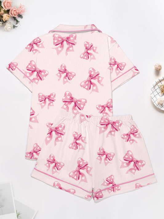 Pastel pink short-sleeve pajama set with heart-dotted bow print — button-up top and elastic waist shorts with pink piping