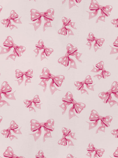 Pastel pink short-sleeve pajama set with heart-dotted bow print — button-up top and elastic waist shorts with pink piping