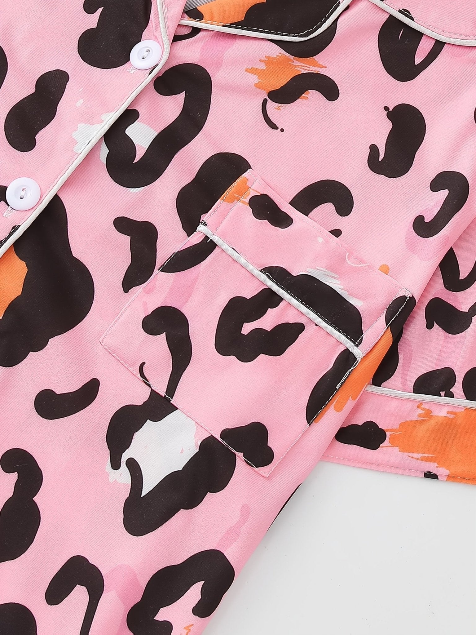 Pink satin-look short-sleeve pajama set with black and orange leopard print, piped trim, chest pocket and elastic waist shorts in 95% Polyester 5% Elastane — silky stretch travel-ready loungewear