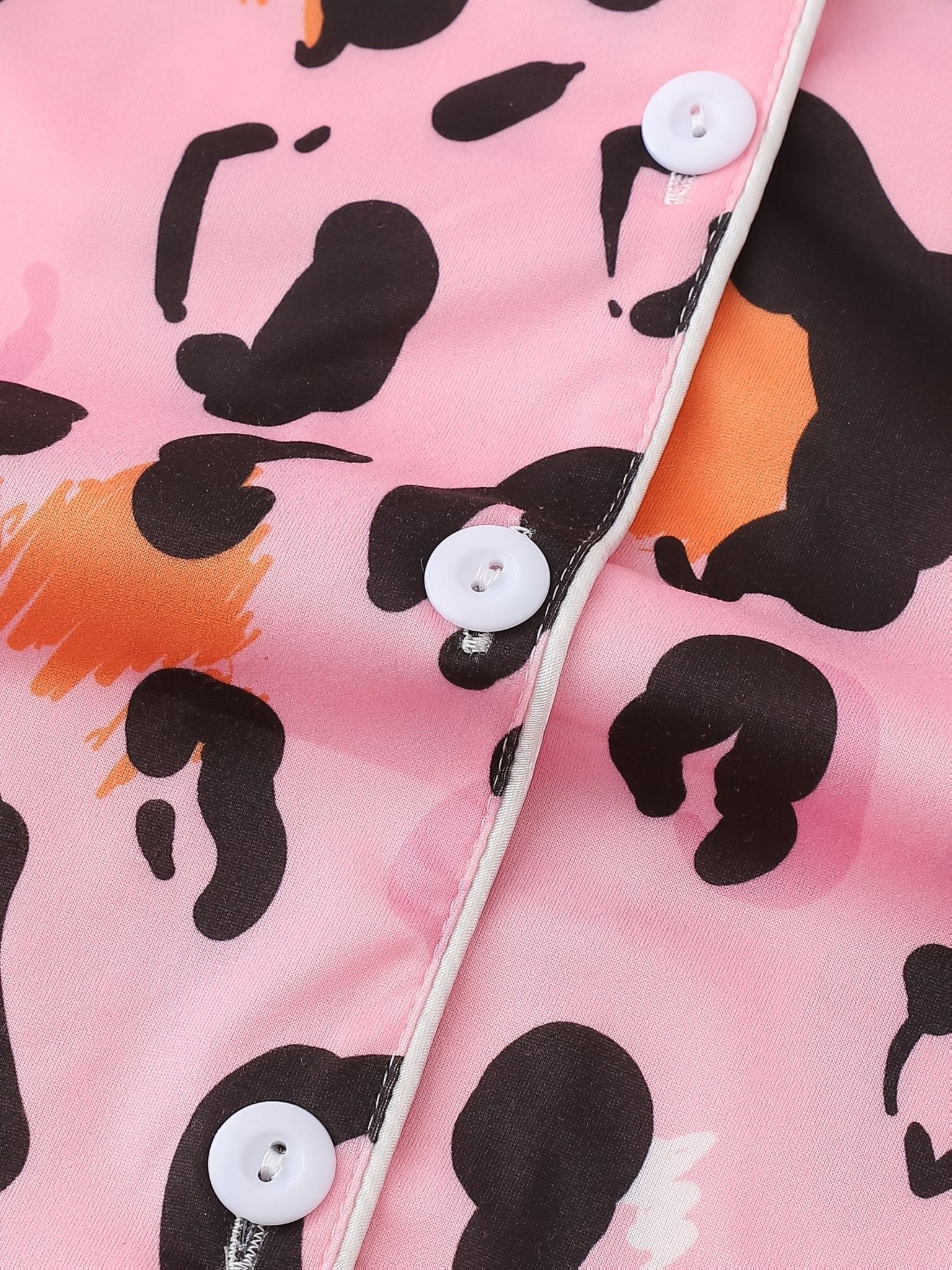 Pink satin-look short-sleeve pajama set with black and orange leopard print, piped trim, chest pocket and elastic waist shorts in 95% Polyester 5% Elastane — silky stretch travel-ready loungewear