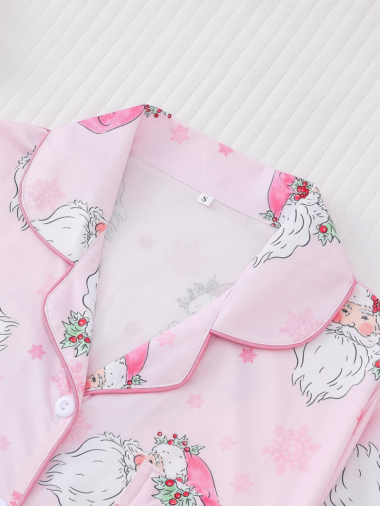 Pink satin-look pajama set with watercolor Santa print and snowflakes, short-sleeve button top with piped pocket and elastic waist full-length pants — 95% Polyester/5% Elastane, silky and breathable