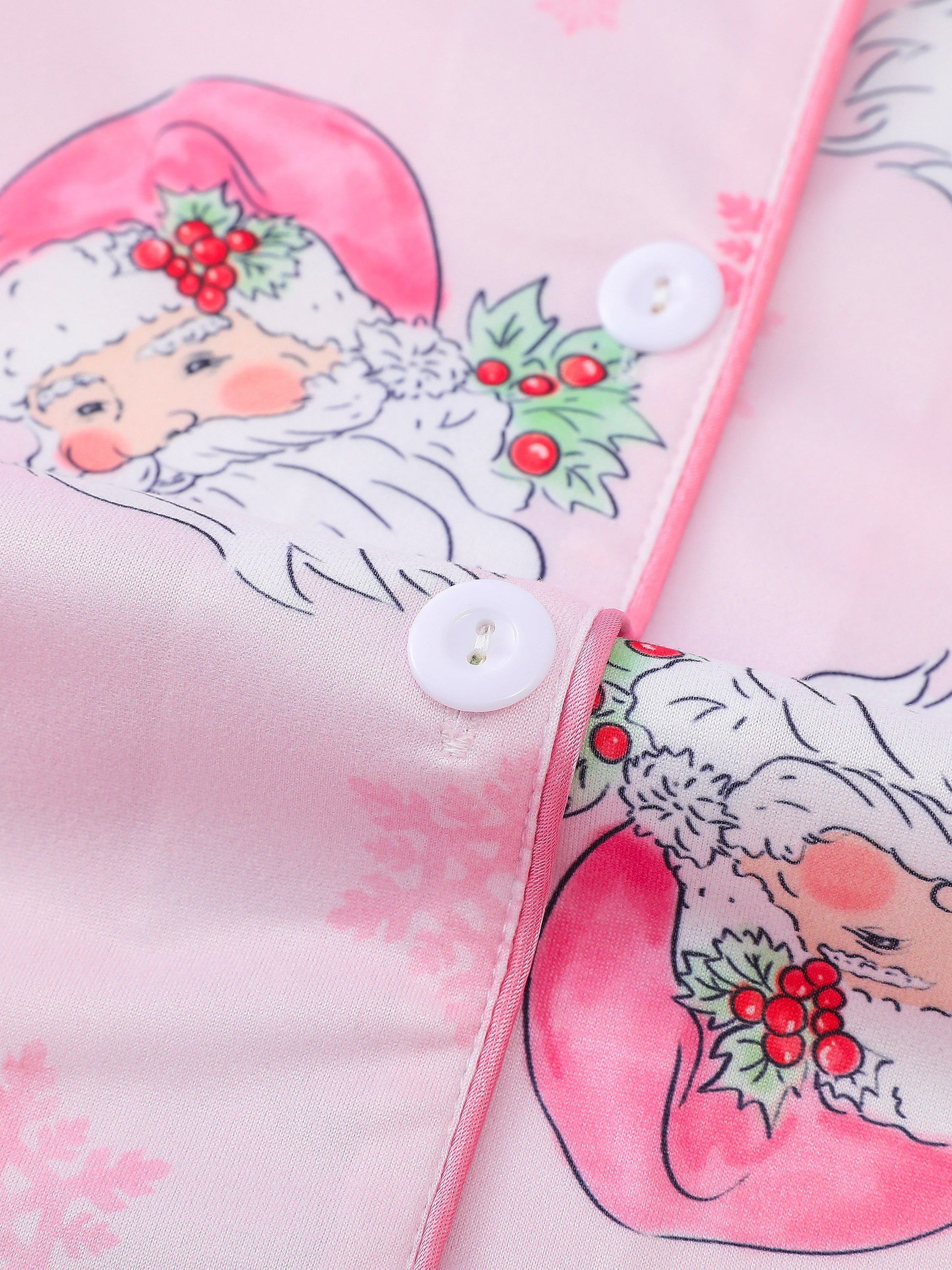 Pink satin-look pajama set with watercolor Santa print and snowflakes, short-sleeve button top with piped pocket and elastic waist full-length pants — 95% Polyester/5% Elastane, silky and breathable