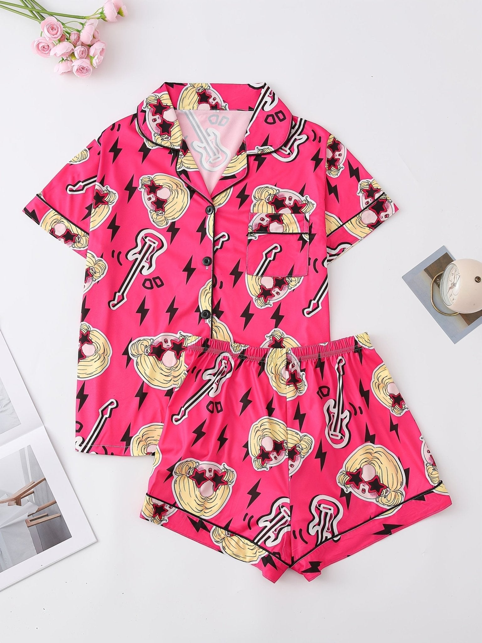 Bright pop-pink satin-look short-sleeve pajama set with guitar and star-sunglasses print, piped trim, chest pocket and elastic waist shorts in 95% Polyester 5% Elastane — silky stretch travel-ready loungewear